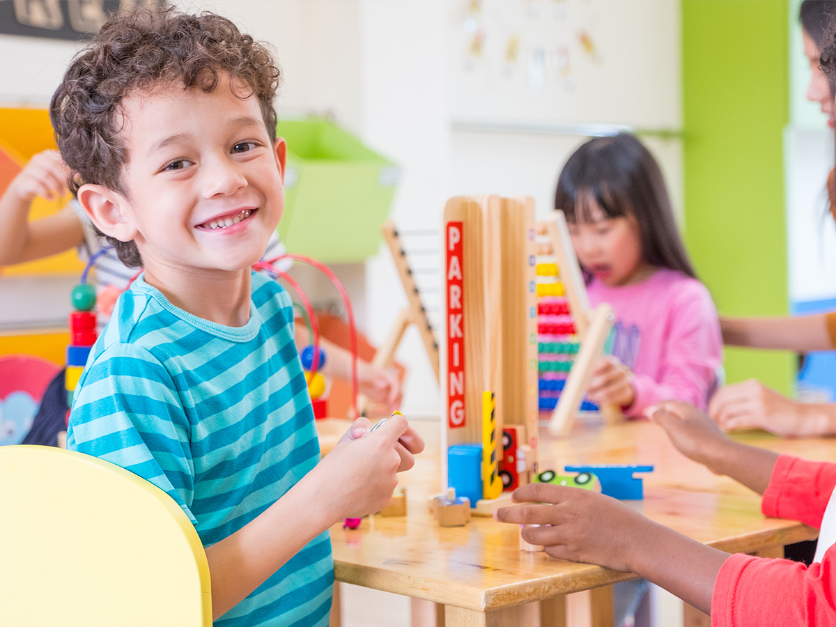Preschool aged boy smiling while playing with building blocks