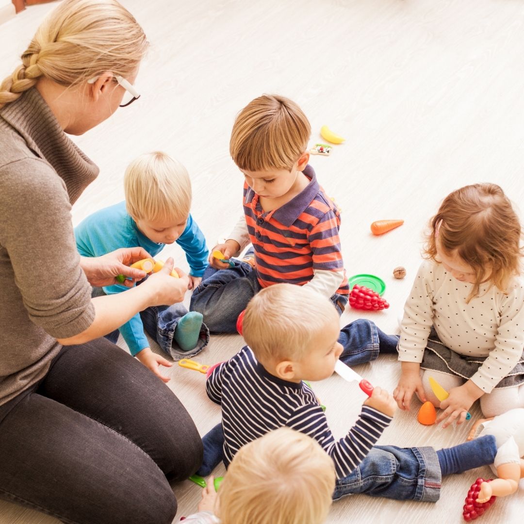 An image of a teacher watching over young children playing.