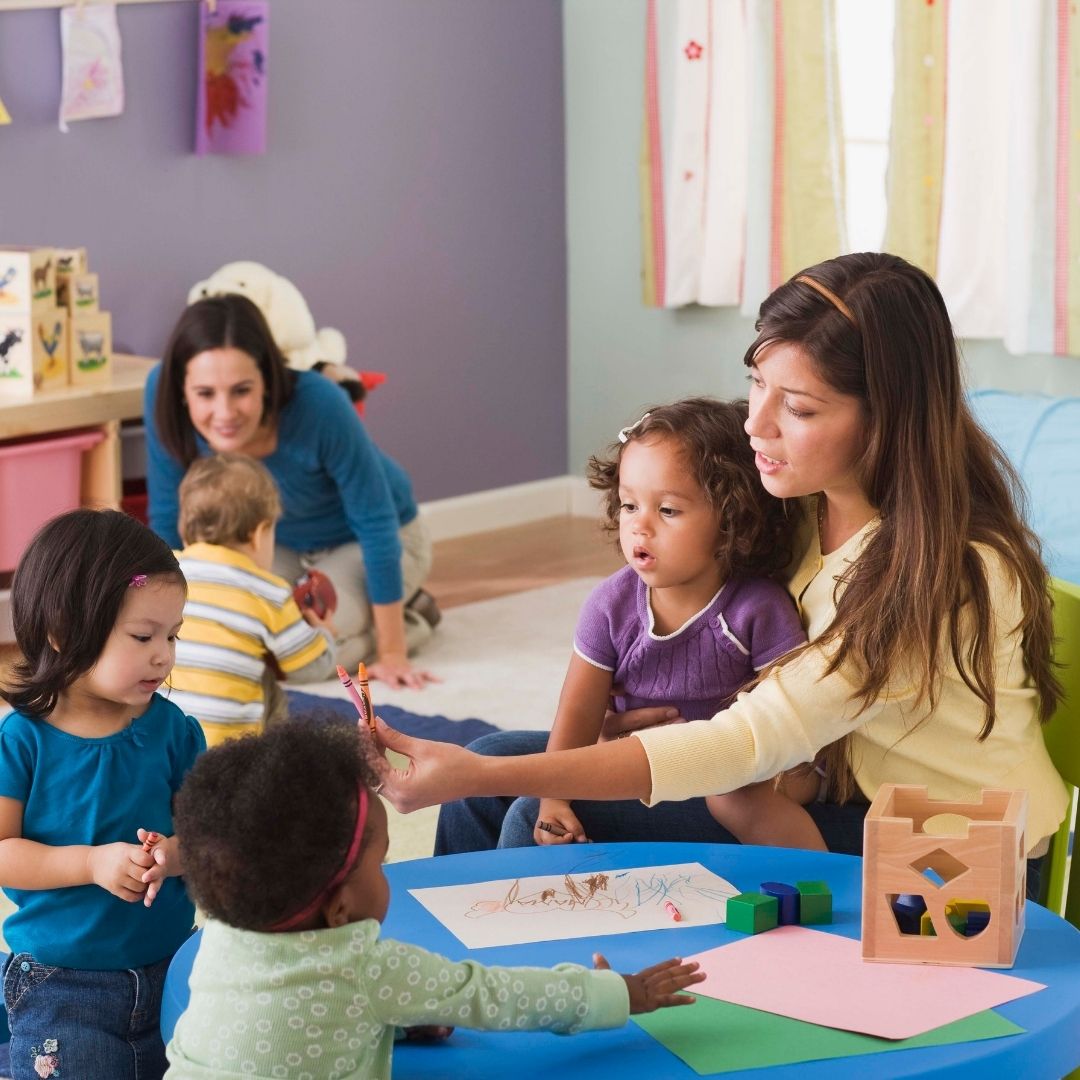 An image of two teachers watching over toddlers in daycare.