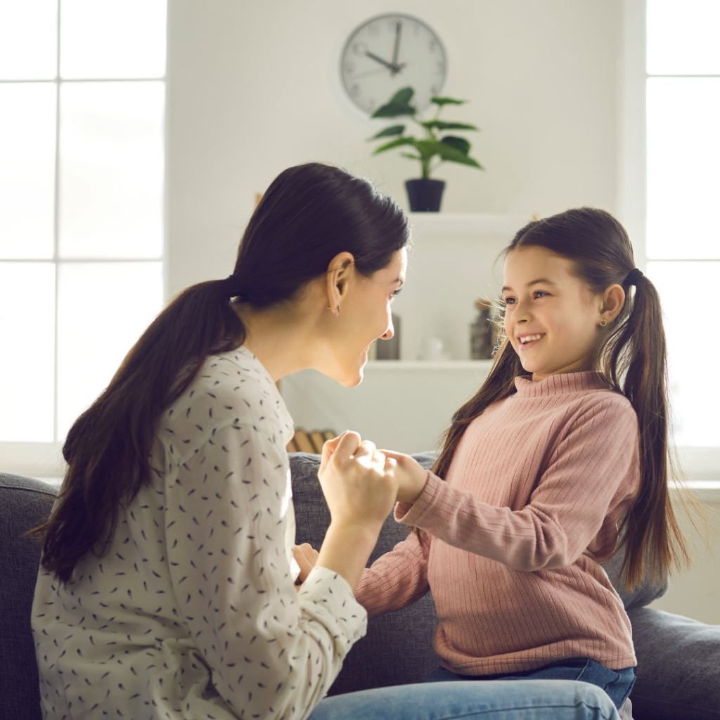 A mother holding her daughters hands while talking to her