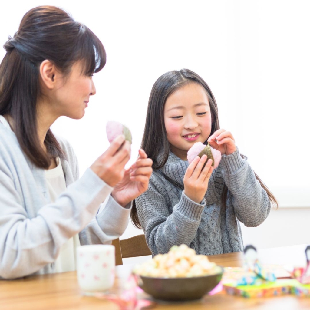 Little girl eating food with her mom