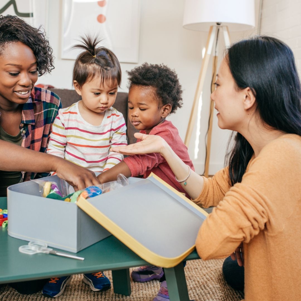 Two mothers helping their children play.