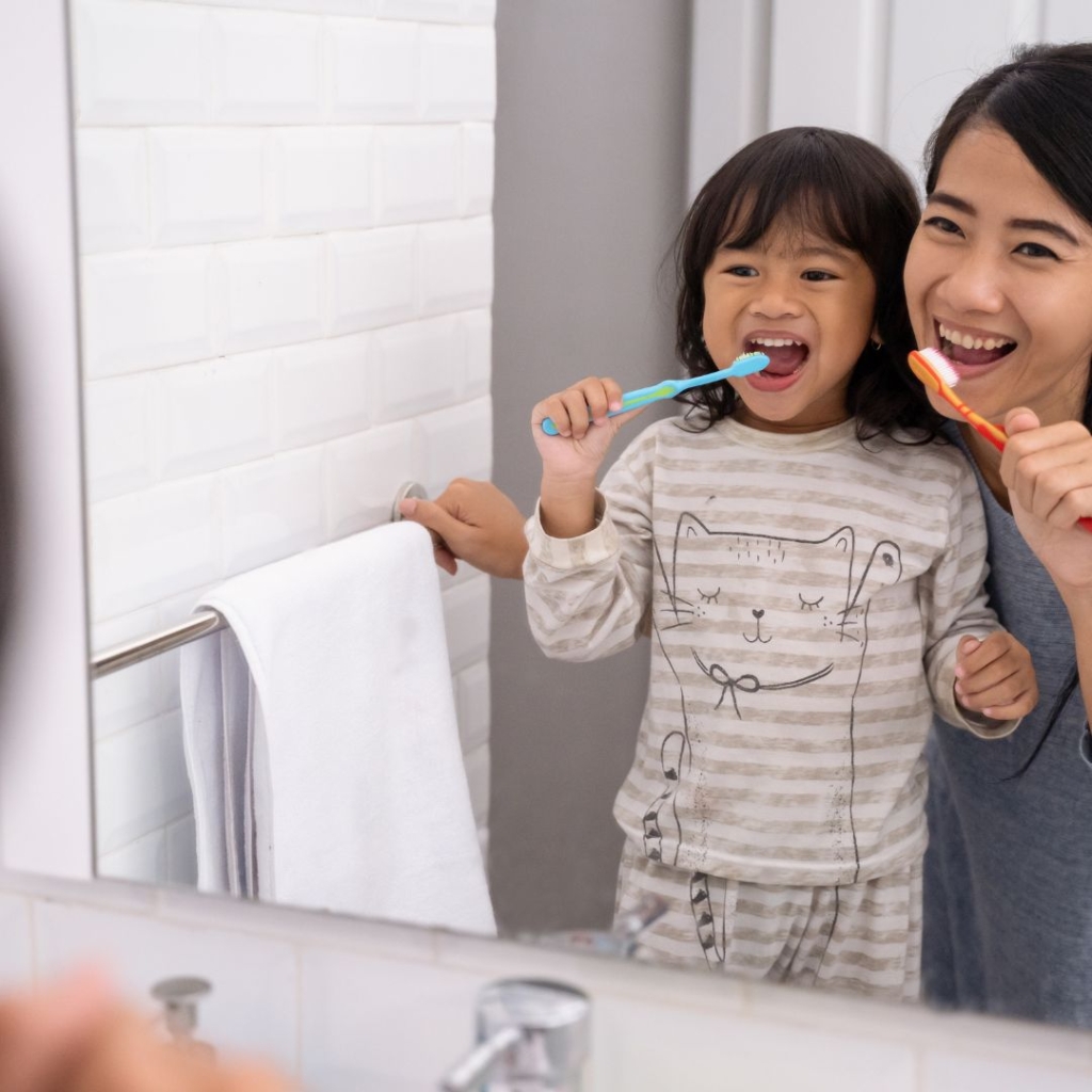 A mother helping her child brush their teeth.
