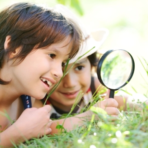kids looking at grass through a magnifying glass