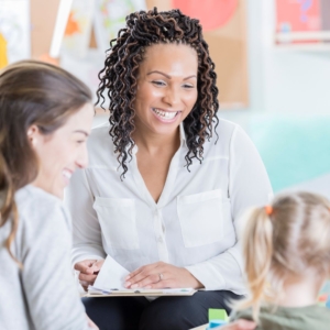 a parent and teacher smiling at a child
