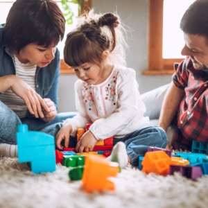 a girl playing with blocks with her parents