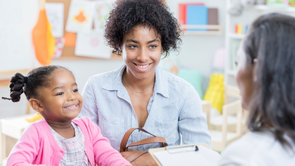 a Mom smiling at a teacher with her daughter