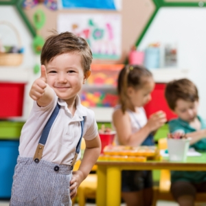 Little boy giving thumbs up in class